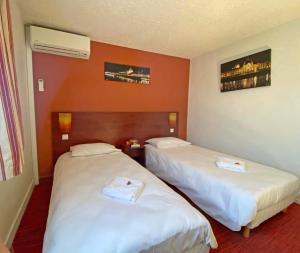 2 camas en una habitación de hotel con paredes rojas en Initial by Balladins Lyon Villefranche-sur-Saône, en Villefranche-sur-Saône