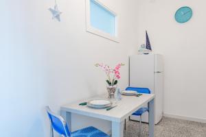 une salle à manger blanche avec une table blanche et des chaises bleues dans l'établissement La conchiglia dei sogni - YourPlace Abruzzo, à Rocca San Giovanni