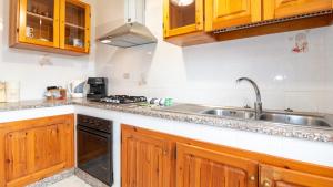una cocina con armarios de madera y fregadero en Su Riu House, en Santa Caterina