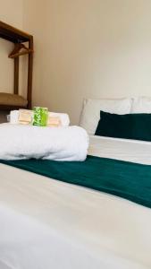 Una cama blanca con toallas verdes y blancas. en Pousada Enero, en Maragogi