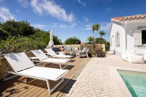 a patio with white lounge chairs and a swimming pool at Seashore Escape in Aljezur