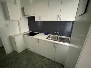 a small kitchen with a sink and white cabinets at Luminoso piso cerca de la playa in Cullera