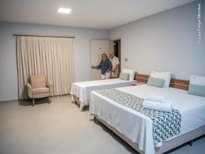 two people standing in a room with two beds at HOTEL AGUAS DE BODOQUENA in Bodoquena