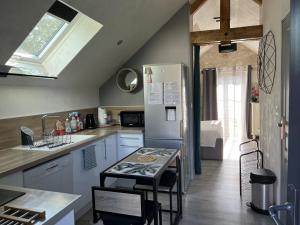 cocina con nevera y mesa con sillas en Gîtes et Chambres des Coteaux en Sainte-Maure-de-Touraine