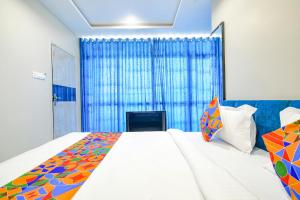 1 dormitorio con 1 cama grande y cortina azul en FabHotel Lake View III, en Indore