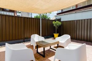 un patio con sillas blancas, una mesa y una valla en Beautiful & Ultra Convenient 4-bdrm Terrace en Sídney