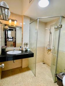 uma casa de banho com um lavatório e uma cabina de duche em vidro. em Kem Apartment 18 Ngô Quyền em Hanói