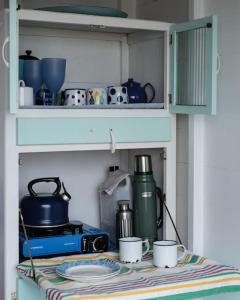 a shelf with cups and dishes on a table at Holiday Cottage with Seafront Beach Hut, Lyme Regis, Dorset in Lyme Regis