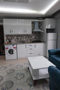 a kitchen with white cabinets and a couch and a table at Çam Suit in Kahramanmaraş