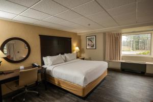 a hotel room with a bed and a desk and a mirror at Peek'n Peak Resort Trademark Collection by Wyndham in Clymer