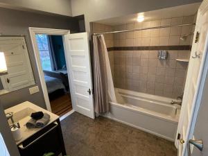 La salle de bains est pourvue d'une baignoire, d'une douche et d'un lavabo. dans l'établissement Oscar's Inn, à Buffalo