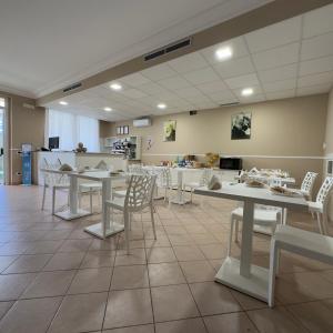 jadalnia ze stołami i białymi krzesłami w obiekcie Hotel Immagine w mieście San Giovanni Rotondo