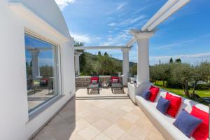 a patio with a couch and chairs and a large window at Villa Serenity garden & pool in Anacapri