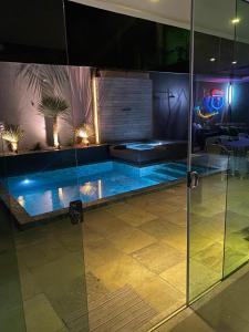 a swimming pool in a room with a glass wall at Casa com Piscina no bairro João VI, Muriaé-MG in Muriaé