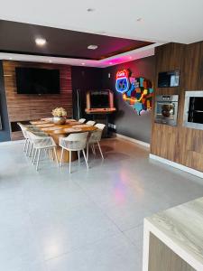 a dining room with a table and chairs and a tv at Casa com Piscina no bairro João VI, Muriaé-MG in Muriaé