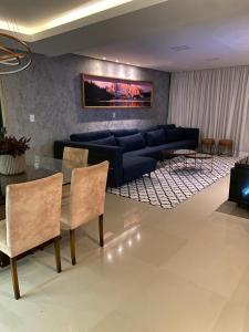 a living room with a blue couch and a table at Casa com Piscina no bairro João VI, Muriaé-MG in Muriaé