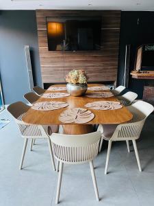 a wooden table with chairs and a bowl of flowers on it at Casa com Piscina no bairro João VI, Muriaé-MG in Muriaé