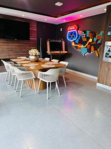 a dining room with a table and chairs and a television at Casa com Piscina no bairro João VI, Muriaé-MG in Muriaé