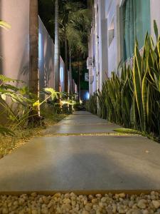a walkway in a city with palm trees and a building at Casa com Piscina no bairro João VI, Muriaé-MG in Muriaé