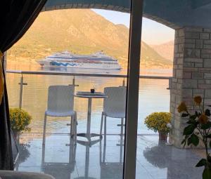 a cruise ship on the water with a table and chairs at ApartHotel Maxim in Kotor
