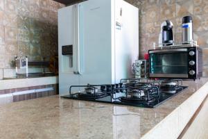 a kitchen with a stove with a microwave and a refrigerator at Casa com Piscina no bairro João VI, Muriaé-MG in Muriaé