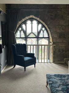 une chaise bleue dans une chambre avec une grande fenêtre dans l'établissement Pottergate Tower, à Alnwick