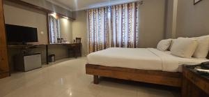 a bedroom with a large bed and a television at Cross Roads Inn in Bangalore