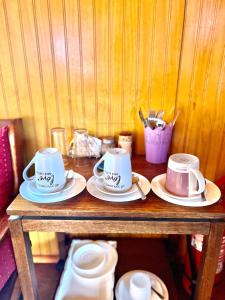 a wooden table with three cups and saucers on it at Hospedaje Familiar Doña Juanita in Puerto Montt
