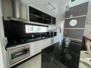 a kitchen with a stove and a clock on the wall at Meia Praia com estilo! 3 suítes, churrasqueira e garagem in Meia Praia +6 photos