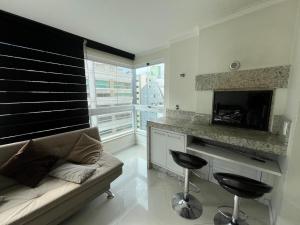 a living room with a couch and a counter with a fireplace at Meia Praia com estilo! 3 suítes, churrasqueira e garagem in Meia Praia