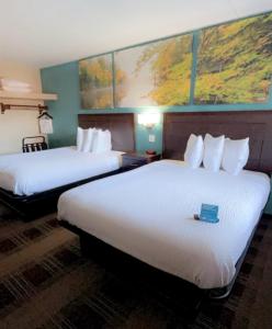 a hotel room with two beds with a book on them at Days Inn & Suites by Wyndham Springfield on I-44 in Springfield