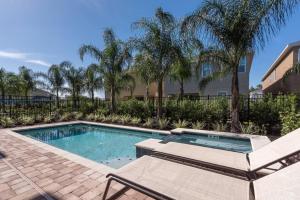 een zwembad met 2 ligstoelen en een zonneklep bij EC464 - Incredible Villa with Themed Games Room at Encore in Orlando