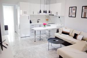 cocina blanca y sala de estar con sofá y mesa en Ermis Mini Suite # 01, en Chalkida