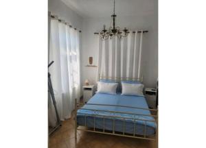 VívlosにあるNaxos Family House in Vivlosのベッドルーム(青いベッド1台、シャンデリア付)