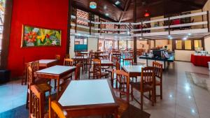 a restaurant with tables and chairs and a red wall at Hotel Fênix in Porto Seguro