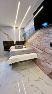 1 dormitorio con pared de piedra, 1 cama y TV en Hotel Bacatá, en Bucaramanga