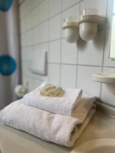 uma pilha de toalhas sentadas num balcão na casa de banho em Hotel Cronberger Hof em Ladenburg