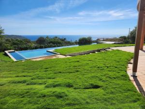 einen Rasenplatz mit Pool und Meer in der Unterkunft Villa La Ronde des Soleils in Coti-Chiavari