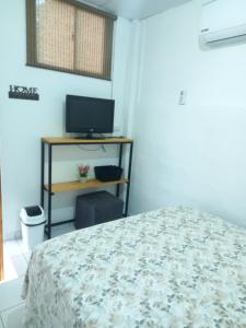 a bedroom with a bed and a desk with a television at blue sky room in San Salvador