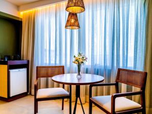 a dining room table with chairs and a vase of flowers at Grand Mercure Rio de Janeiro Copacabana in Rio de Janeiro