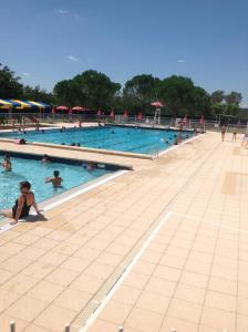 een groot zwembad met veel mensen erin bij Ancien presbytere au coeur du village in Mauvezin