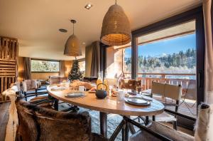 a dining room with a table and chairs and a large window at Chalet Virolo in Megève