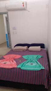 Una cama con mantas de colores encima. en Soul do Mar Hostel, en Cabo Frío