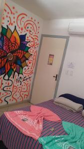 a bedroom with a bed with a painting on the wall at Soul do Mar Hostel in Cabo Frio