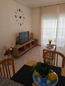 a living room with a table and a clock on the wall at Sandy Home - Élvezd a tengerpartot! in La Mata
