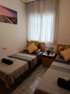 a bedroom with two beds and a window at Sandy Home - Élvezd a tengerpartot! in La Mata +10 photos