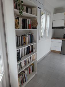 una estantería llena de libros en una cocina en Appartement cosy au calme à cote du zoo avec balcon et parking securisé en Montpellier