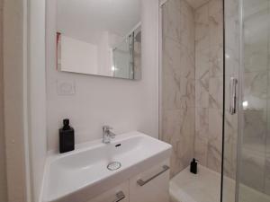 a white bathroom with a sink and a shower at Palerme - Appart'city in Reims