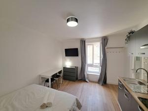 a bedroom with a bed and a desk and a kitchen at Palerme - Appart'city in Reims