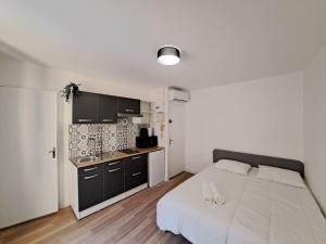 a bedroom with a large white bed and a kitchen at Palerme - Appart'city in Reims